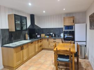 una cucina con armadi in legno, tavolo e frigorifero di Le Refuge Comtois a La Longeville Altre 9 foto