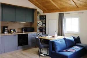 ein Wohnzimmer mit einem blauen Sofa und einer Küche in der Unterkunft Natur- und Aktivresort Senftenberg in Schipkau