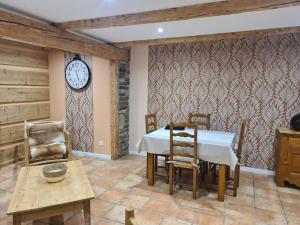 ein Esszimmer mit einem Tisch und einer Uhr an der Wand in der Unterkunft La ferme d Istrie in La Longeville