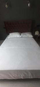 uma cama com lençóis brancos e almofadas num quarto em Lux Aparments Guramishvili em Tbilisi