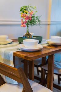 a wooden table with plates and a vase with flowers at Cozy and quirky Wolf Apartment in Paramaribo