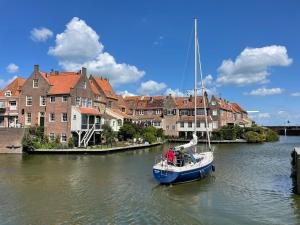 un hombre en un velero en un río con casas en Hotelhuisjes Medemblik en Wieringerwerf