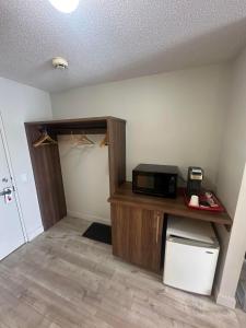 a room with a desk with a microwave and a closet at Hôtel Motel Le Voyageur in Saint-Georges
