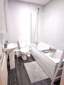 a bathroom with a toilet and a tub and a sink at Apartment 2 St. Marks Court in Anlaby