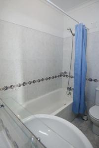 baño con bañera, aseo y cortina de ducha azul en STUDIO COMPLETO PARA 2 PESSOAS, en Albufeira