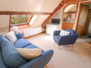 a living room with a blue couch and two chairs at The Granary in Llandyfrydog