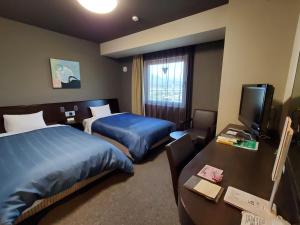 una camera d'albergo con due letti e una televisione di Hotel Route-Inn Dai-ni Kameyama Inter a Kameyama