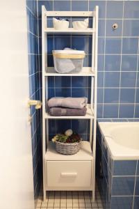 - une étagère blanche dans une salle de bains pourvue de serviettes et d'un lavabo dans l'établissement Ferienwohnung am Oberen Schloss, à Siegen