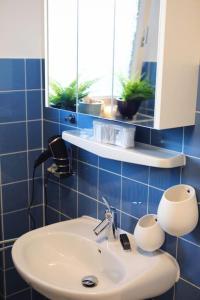 La salle de bains est pourvue de carrelage bleu, d'un lavabo et d'un miroir. dans l'établissement Ferienwohnung am Oberen Schloss, à Siegen