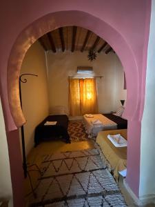 a room with an arch with two beds and a window at Kasbah Erg Chebbi in Merzouga