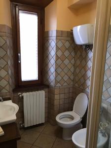 un bagno con un water, un lavandino e una finestra di Casa La Quercia a Chiusi della Verna