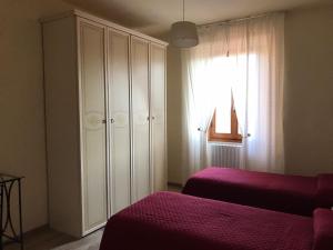una camera con due letti, un armadio e una finestra di Casa La Quercia a Chiusi della Verna