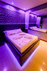 2 camas en una habitación con iluminación púrpura en Motel I Love Pelotas, en Pelotas