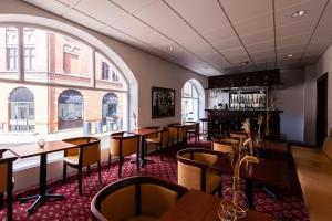 a restaurant with tables and chairs and large windows at Milling Hotel Windsor in Odense