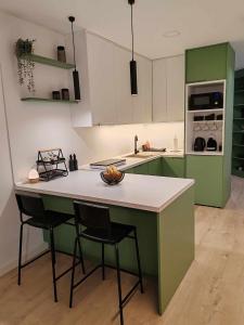 uma cozinha com armários verdes e um balcão com duas cadeiras em Apartman „Karolina” em Nova Gradiška