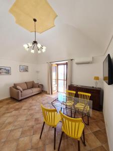 een woonkamer met een glazen tafel en gele stoelen bij Casa Monticello in Positano