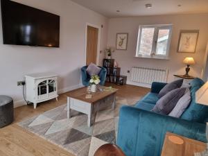 a living room with a blue couch and a tv at Begonia Cottage in Briston