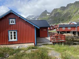 a red house with a wooden deck in front of a mountain at Elisabeth-Bua in Moskenes