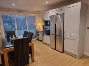 a kitchen with a dining table and a refrigerator at Begonia Cottage in Briston