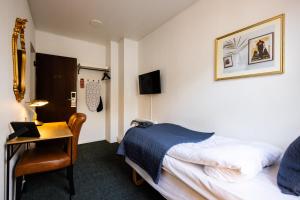a hotel room with a bed and a desk with a laptop at Milling Hotel Windsor in Odense