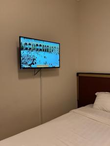 a flat screen tv hanging on a wall above a bed at فندق رشيد الفضي in Az Zahrāʼ