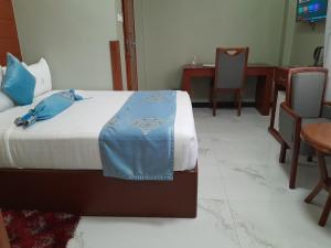 sypialnia z łóżkiem, stołem i krzesłami w obiekcie HOTEL MDOPE MBEYA w Mbeya