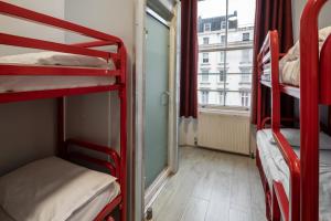 um quarto com 3 beliches e uma janela em Astor Victoria Hostel em Londres