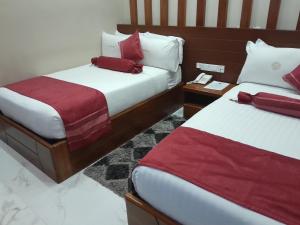2 camas en una habitación de hotel con sábanas rojas y blancas en HOTEL MDOPE MBEYA, en Mbeya