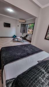 a bedroom with a large bed in a room with windows at Casa Carandá in Campo Grande