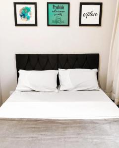Una cama con sábanas blancas y almohadas en un dormitorio en Hostel Flamengo, en Río de Janeiro