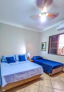 a bedroom with two beds and a ceiling fan at Casa Carandá in Campo Grande