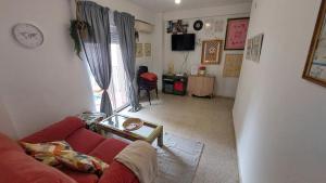 a living room with a red couch and a clock at Céntrico piso con aparcamiento gratuito in Granada
