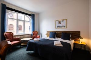 a bedroom with a bed and chairs and a window at Milling Hotel Windsor in Odense