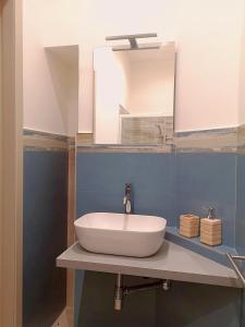 een badkamer met een witte wastafel en een spiegel bij Dietro Piazza Duomo in Acireale
