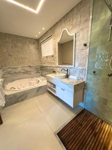 a bathroom with a tub and a sink and a bath tub at Pousada Praia do Funil in Lajeado