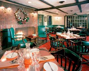 un ristorante con tavoli, sedie e un camino di The Olde Mill Inn Basking Ridge a Basking Ridge