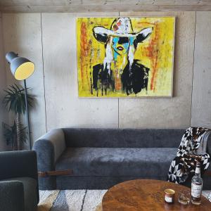 a living room with a couch and a painting of a cow at Yellowstone Peaks Hotel in Island Park