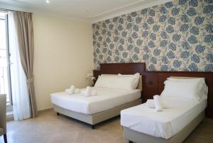 two beds in a hotel room with white sheets at Glam Luxury Rome in Rome