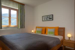 Apartment 148 with panoramic view of Lake Hallstatt في هالشتات: غرفة نوم مع سرير مع وسائد برتقالية وأخضر