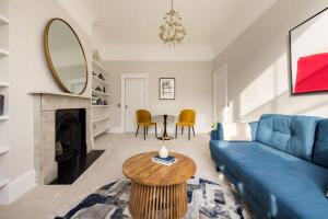 a living room with a blue couch and a table at Chic & Sunlit Earls Court Flat in London