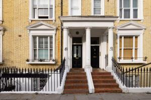 a brick house with a white front door and stairs at Chic & Sunlit Earls Court Flat in London