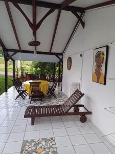 eine Terrasse mit einem Tisch, Stühlen und einer Bank in der Unterkunft La petite perle in Ducos