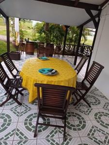 une table et des chaises jaunes sur une terrasse dans l'établissement La petite perle, à Ducos