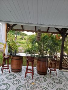 eine Terrasse mit einer Bar mit Hockern unter einem Baldachin in der Unterkunft La petite perle in Ducos