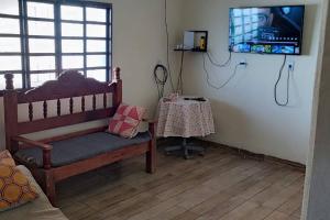 a room with a bench and a table with a television at Chácara 15km Tecnoshow Rio Verde in Rio Verde