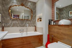 a bathroom with a tub and a sink and a mirror at Luxury Bermondsey Warehouse Loft with Lift in London