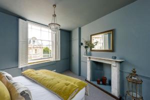 a blue bedroom with a bed and a fireplace at Divine Georgian Townhouse in the heart of Bath in Bath