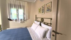 a bedroom with a bed with white pillows and a window at Rizes House II in Agios Nikolaos