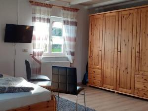 um quarto com uma cama, um armário e uma janela em Holiday apartment Küber em Altusried