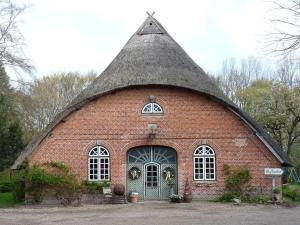 duży budynek z czerwonej cegły z dachem krytym strzechą w obiekcie at the organic farm Angus-Hof w mieście Stakendorf